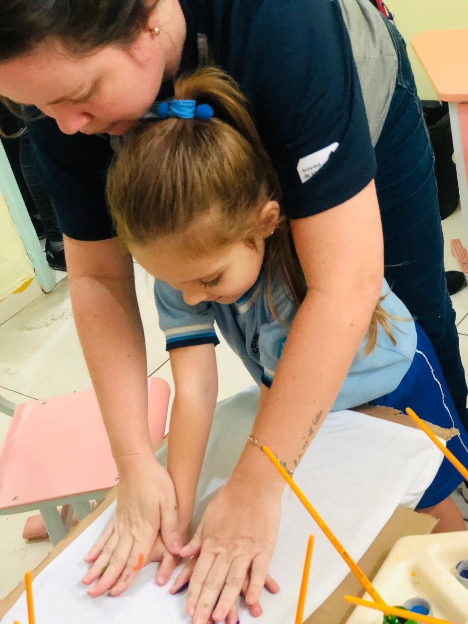 Uma aluna da Educação Infantil do Colégio Baronesa e sua professora fazendo a arte da mão